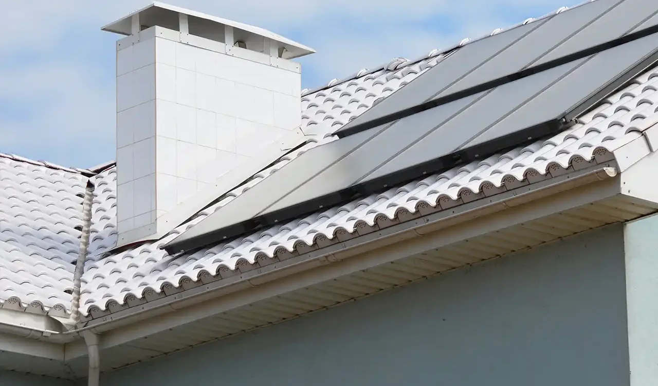 White tile roof featuring solar panels and clean white soffit trim under a cloudy sky
